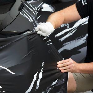 pexels-photo-17641807-17641807 Man working in a garage, applying a vinyl wrap to a vehicle for customization.